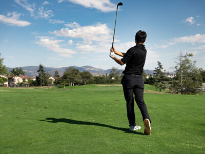 A teenage boy holds his backswing.